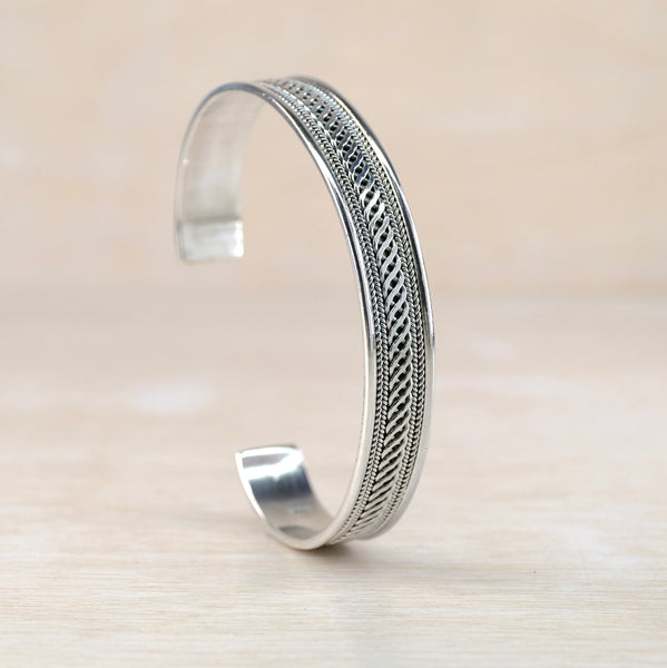 Silver bracelet with intricate design on a beige background