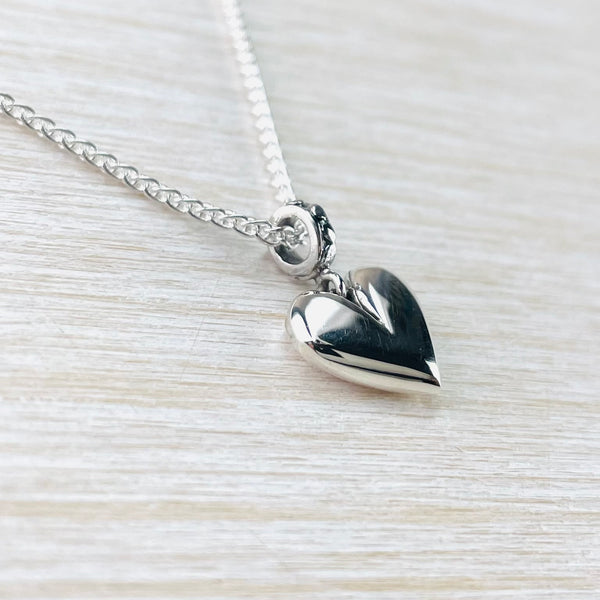 a solid silver heart endant on a silver chain with a decorative bale a solid silver heart endant on a silver chain with a decorative bale
