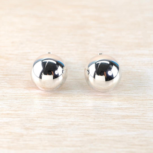 Pair of silver round domed earrings on a light wood background