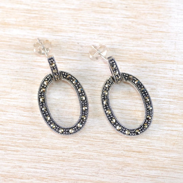 Pair of hoop earrings with marcasite stones on a light wood surface Pair of hoop earrings with marcasite stones on a light wood surface