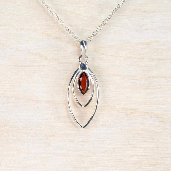 red garnet gemstone in a marquise shaped sterling silver pendant on a hain.