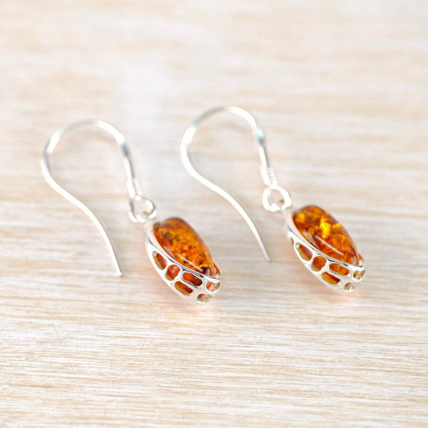 Silver earrings with amber stones on a light wooden surface