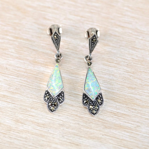Pair of silver earrings with opal stones on a light wood background