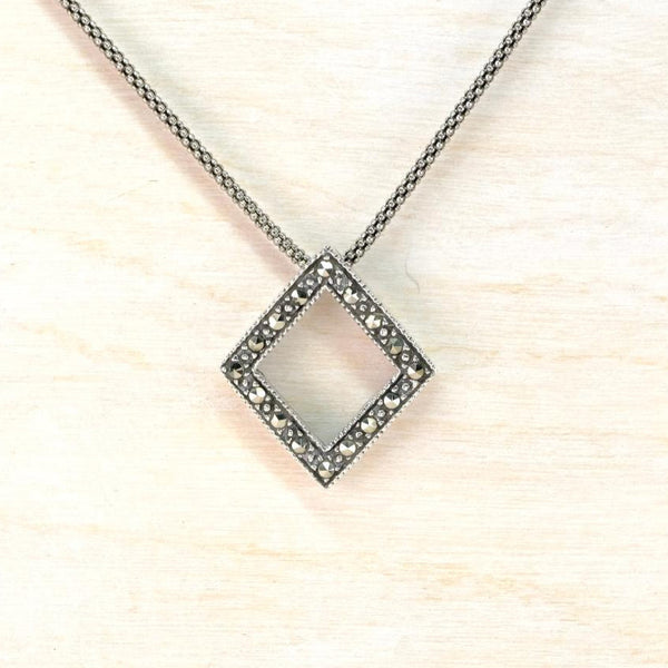 Necklace with a square pendant on a light wooden surface