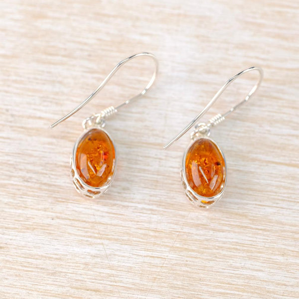 Pair of amber stone earrings on a light wood surface Pair of amber stone earrings on a light wood surface