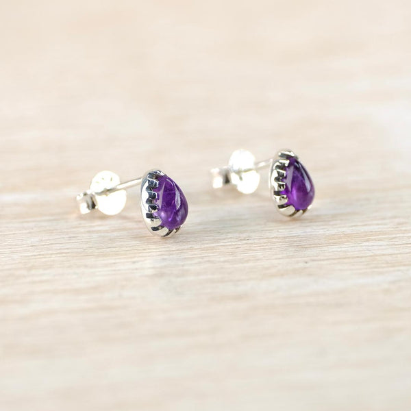 Pair of purple teardrop earrings on a light wooden surface