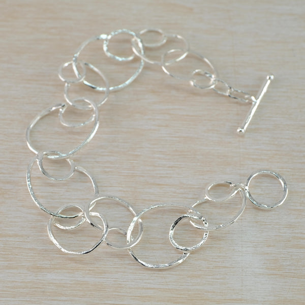 Seventeen open circles linked together to form the length of the bracelet. The links are super shiny silver , and have a slight wave around their circular shape which further catches the light. Classicly elegant.