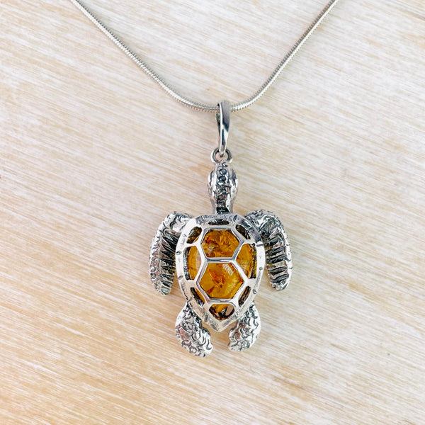 A silver turtle with all silver head, flippers and feet, has an amber body with silver 'shell' shapes which look like armour attached to the body.