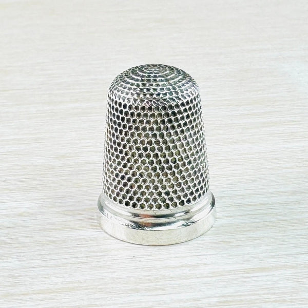 silver thimble is covered with little hexagonal shapes, the insides of which are almost black. The hallmark is visiable on a plain silver band on the bottom.