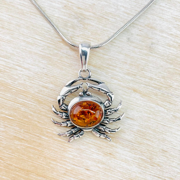 Crab shaped pendant with orange amber forming the body and sterling silver the claws and pincers. 