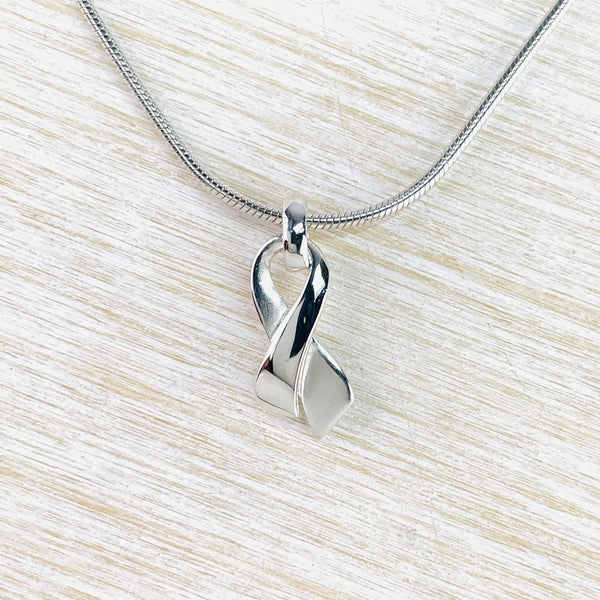 Little pendant that looks like a crossed over ribbon hanging from a chain. One half is matt, the other polished.