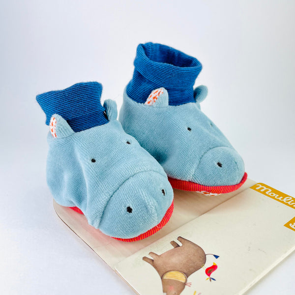 Blue bootie type slippers. The main part of the slipper is a friendly pale blue hippo face with two smll nostrils, two small eyes and little ears with a floral backing. The top bit of the slipper is a dark blue sock with a turn over top.