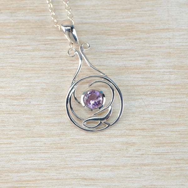 Silver pendant with a lilac gemstone on a beige woven background