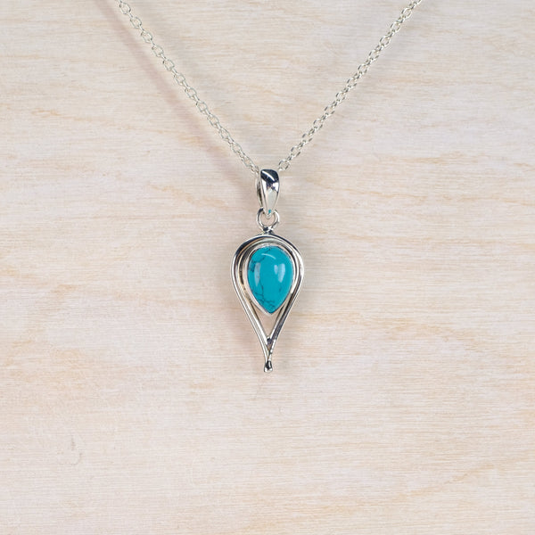 Silver necklace with a turquoise pendant on a light wood background