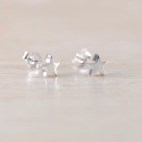 Silver star-shaped earrings on a light wooden surface