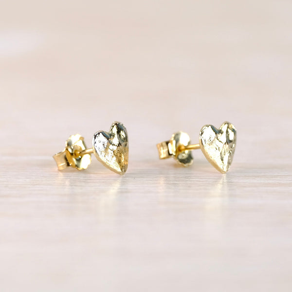 Heart-shaped gold earrings on a light background