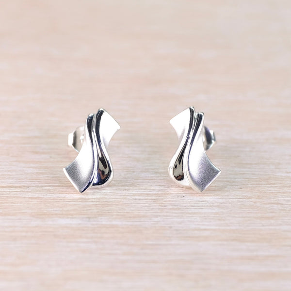 Pair of silver earrings on a light wood surface