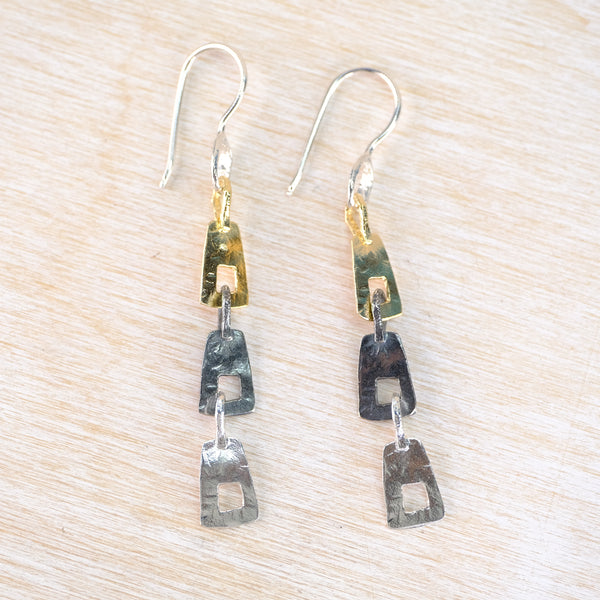 Pair of long silver and gold earrings with three linked geometric elements.
