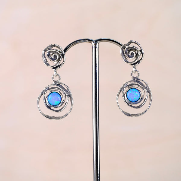 Pair of silver earrings with blue gemstones on a beige background