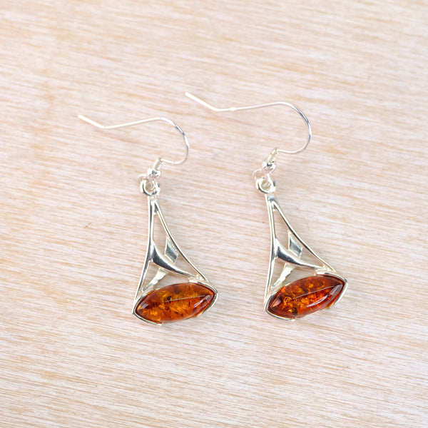 Silver earrings with amber stones on a light wood surface