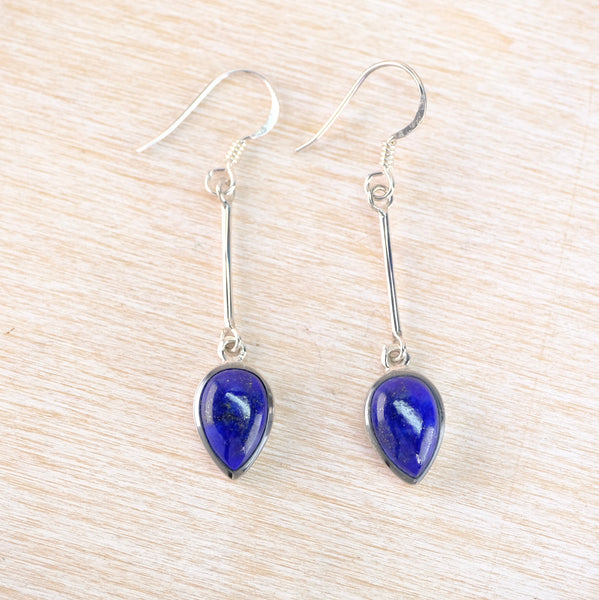 Pair of blue teardrop earrings on a light wood surface