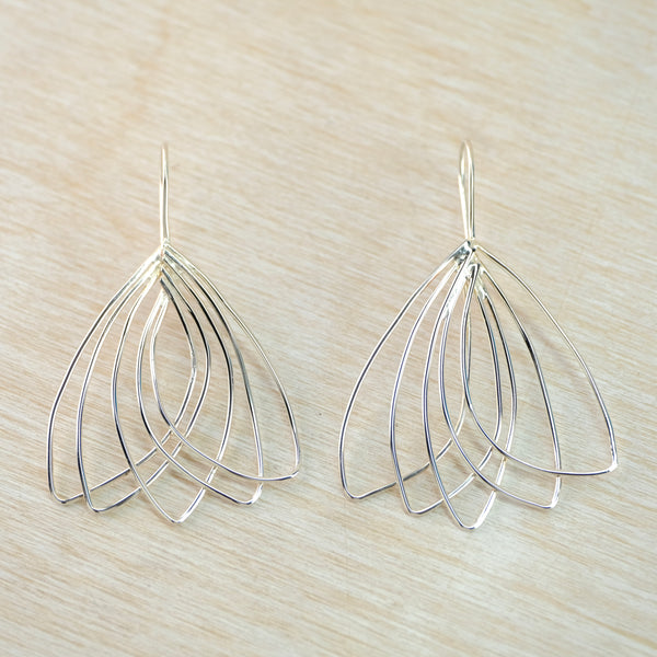 Silver wire earrings on a light wood surface