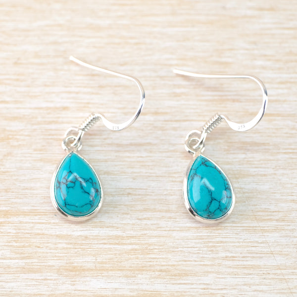 Turquoise teardrop earrings on a light wood background
