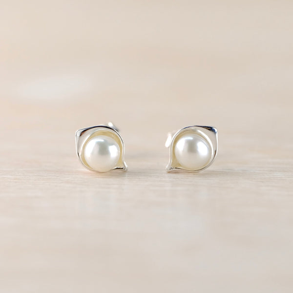 Pearl earrings on a light wooden surface