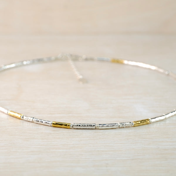 Silver and gold necklace on a light beige background