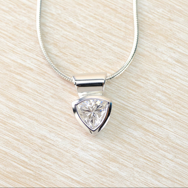 Trillion cut cz pendant on a silver chain against a beige background