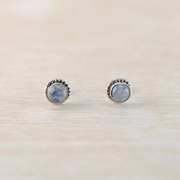 Round silver earrings with gemstones on a beige surface