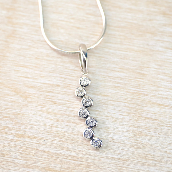 Silver necklace with a pendant on a light wood surface