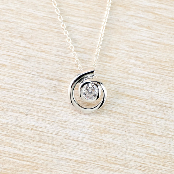 Silver necklace with a cz pendant on a light wood background