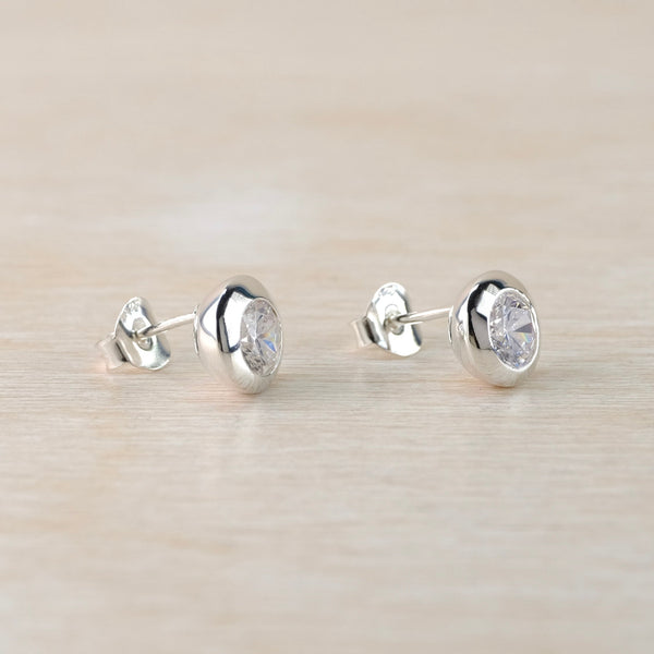 Pair of silver stud earrings on a light beige background