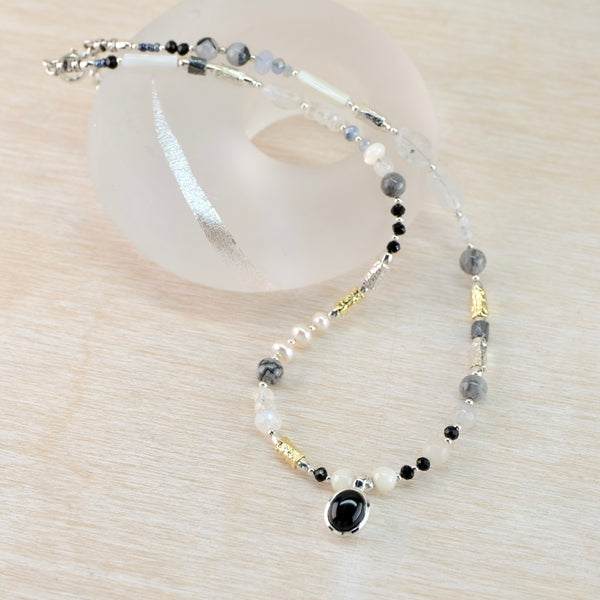 Necklace with beads and a black stone on a white background