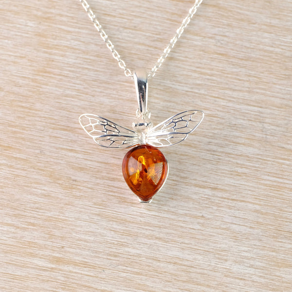 Silver pendant with amber center on a light wood background