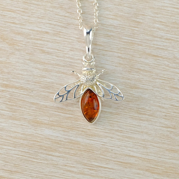 Silver bee pendant with amber stone on a beige background