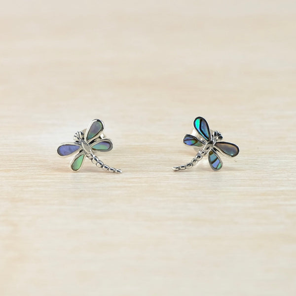 Dragonfly-shaped earrings on a beige background