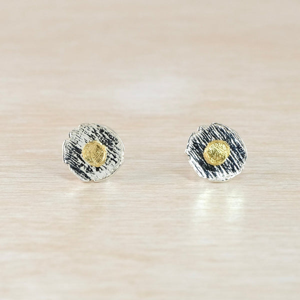 Pair of organically round stud earrings with gold center on a beige background
