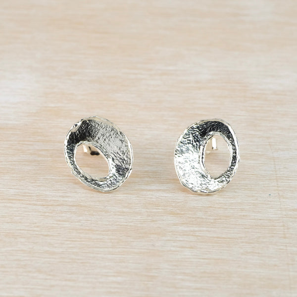 Pair of silver open oval stud earrings on a light wood surface