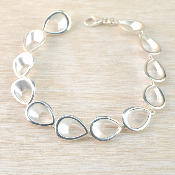 A silver bracelet formed of twelve identical links which have an open  and three-dimensional teardrop shape. The links are joined at the back by secure soldered rings which give the bracelet an attractive fluidity around the wrist.