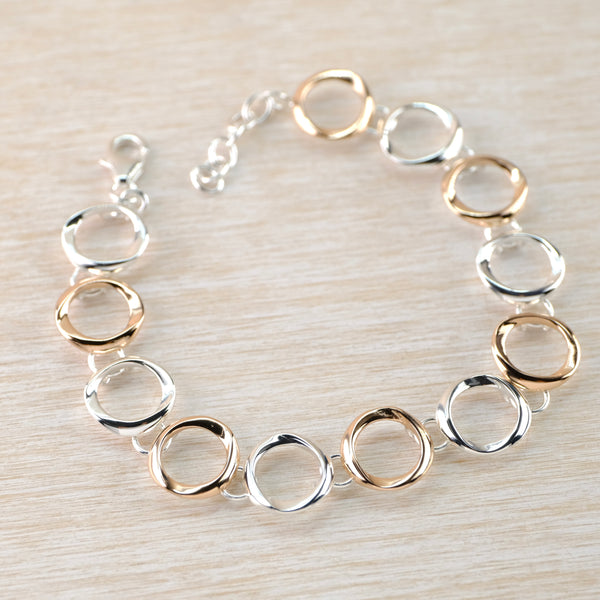 A link bracelet. The links are open circles, but slightly organic in shape rather than perfectly geometric. Links are joined at the back, so nearly invisibly , by skilfully putting rings through loops, so that it sits fluidly around the wrist. Links alternate between high polished silver and rose-gold plated silver.