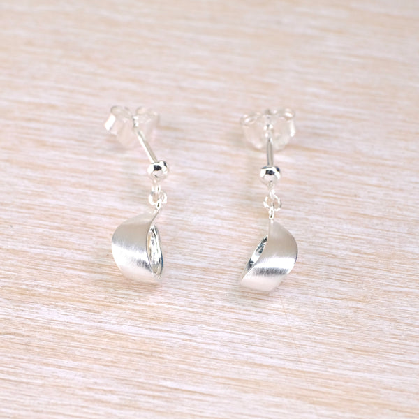 Pair of silver earrings on a light wood surface