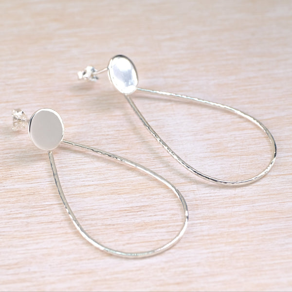 silver earrings with an open teardrop shape below flat oval studs