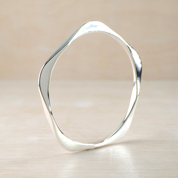 Silver banglee with a modern design on a beige background