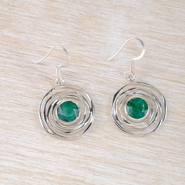 earrings with an emerald green gemstone and a silver spiral design surround