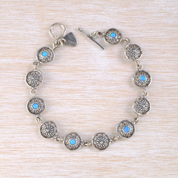 Silver bracelet with  eleven circular links. six of which are set with blue stones . The silver links have pretty almost floral decorations.