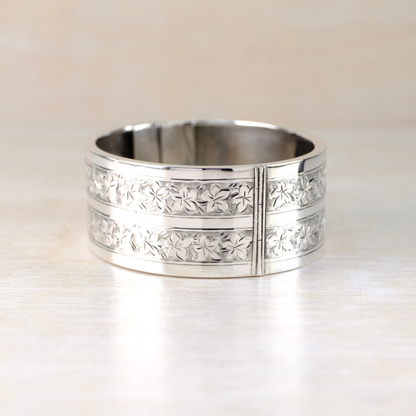 A silver bangle bracelet with fine engraving of leaves all around its sides.