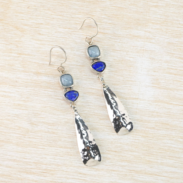 Silver earrings with blue stones on a beige background