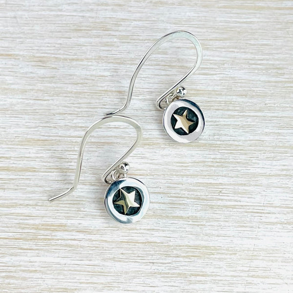 A pair of silver and gold round drop earrings with a star in the middle